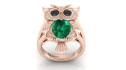Rose gold owl ring with a green gemstone on a white background