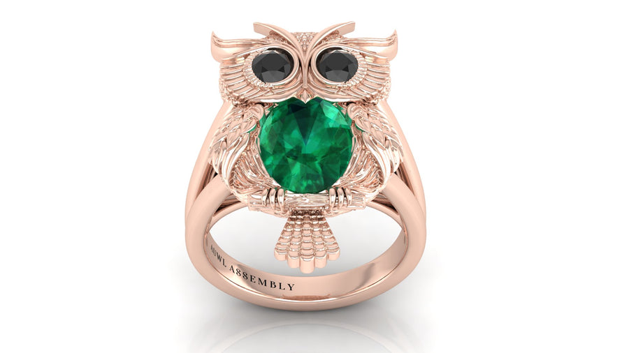 Rose gold owl ring with a green gemstone on a white background