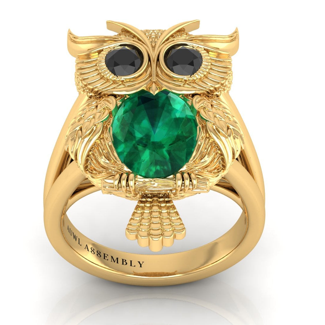 Gold owl-shaped ring with a green gemstone on a white background