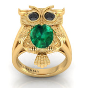 Gold owl-shaped ring with a green gemstone on a white background