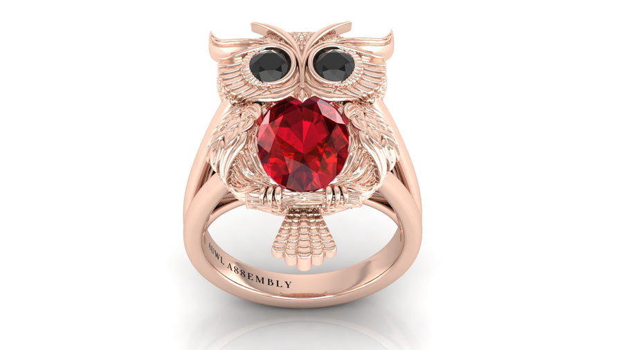 Rose gold owl ring with a ruby gemstone on a white background
