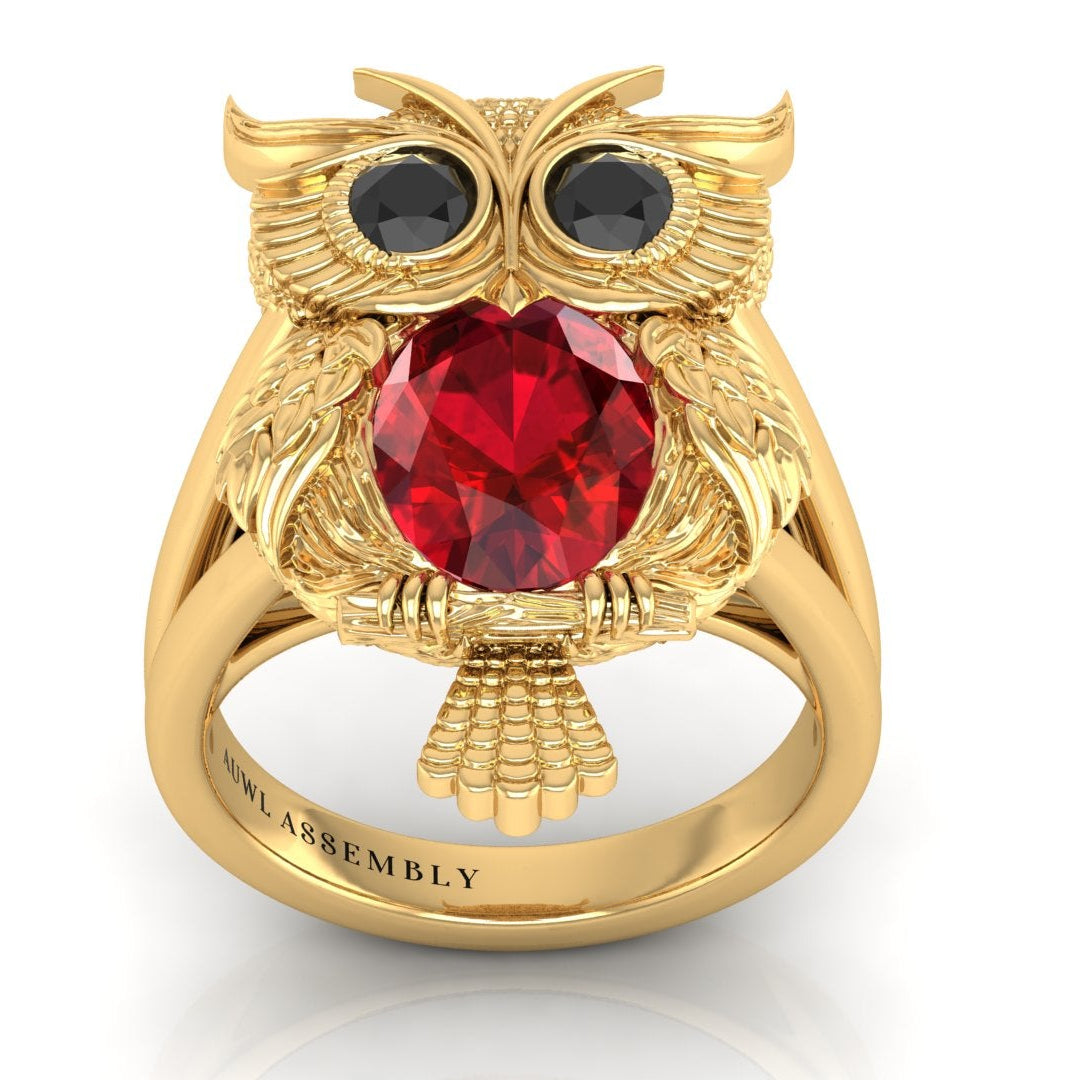 Gold owl-shaped ring with a ruby gemstone on a white background