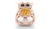 Rose gold owl ring with a yellow sapphire gemstone on a white background