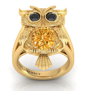 Gold owl-shaped ring with a yellow sapphire gemstone on a white background
