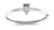 A polished white gold bangle bracelet featuring a small owl charm with black eyes and a Diamond gemstone, shown on a clean white background.