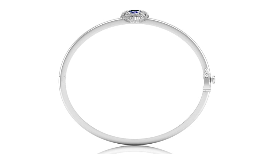 A polished white circular bangle bracelet with a small oval Blue sapphire gemstone and surrounding clear stones at the top, shown on a white background.