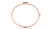 A slim rose gold bangle bracelet with a small green oval gemstone and tiny clear stones at the top, shown on a plain white background.