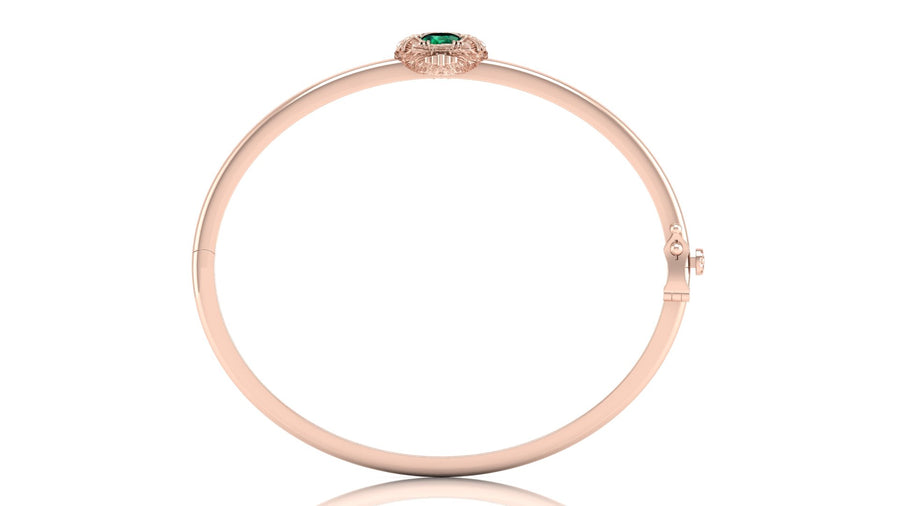 A slim rose gold bangle bracelet with a small green oval gemstone and tiny clear stones at the top, shown on a plain white background.