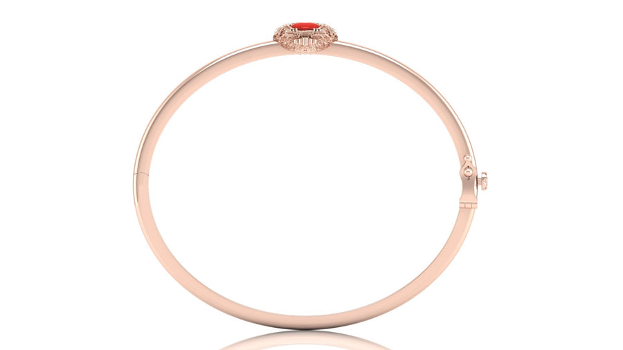 A slim rose gold bangle bracelet with a small red coral centre stone and clear accent stones at the clasp, shown on a white background with a soft reflection.