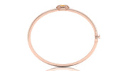 A slim rose gold bangle bracelet with a small yellow sapphire gemstone accent at the top, displayed on a clean white background.