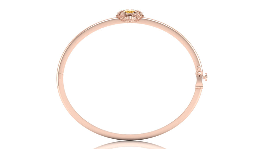 A slim rose gold bangle bracelet with a small yellow sapphire gemstone accent at the top, displayed on a clean white background.
