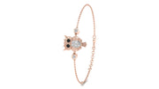 A delicate rose gold chain bracelet featuring an owl charm with black eyes and a central cluster of clear stones, accented with small round clear stones, shown on a plain white background.