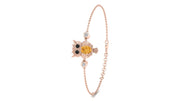 A delicate rose gold chain bracelet featuring a central owl charm with a yellow sapphire centrepiece, black eyes, and small clear stones, shown on a plain white background.