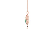 A rose gold pendant shaped like a sleeping owl, featuring a textured finish and a small green emerald centrestone on its wing, hanging from a delicate rose gold chain against a white background.