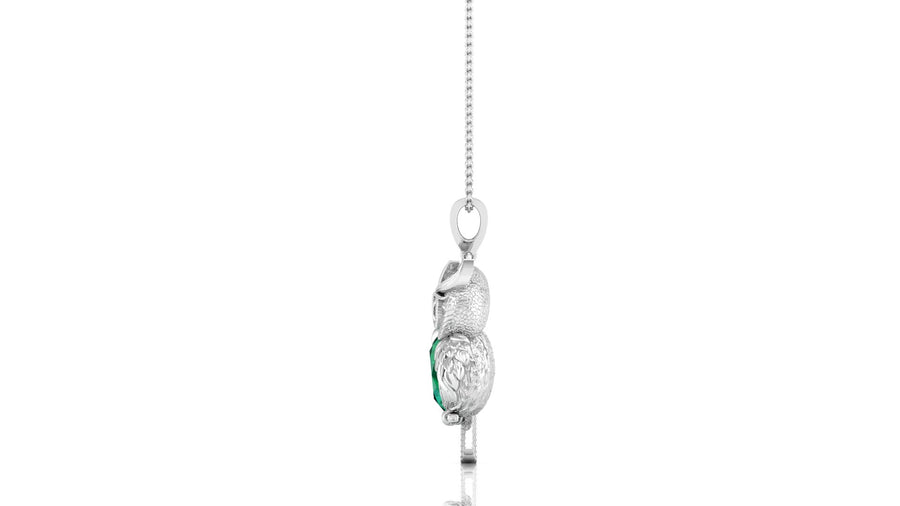 A white gold pendant necklace featuring a stylized bird design with a textured body and a small green emerald gemstone accent, suspended from a delicate silver chain against a white background.