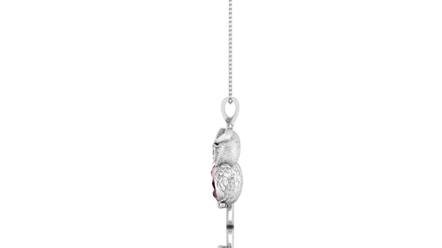 A white gold pendant necklace featuring a detailed bird charm with a red ruby gemstone centre, suspended from a delicate silver chain against a plain white background.