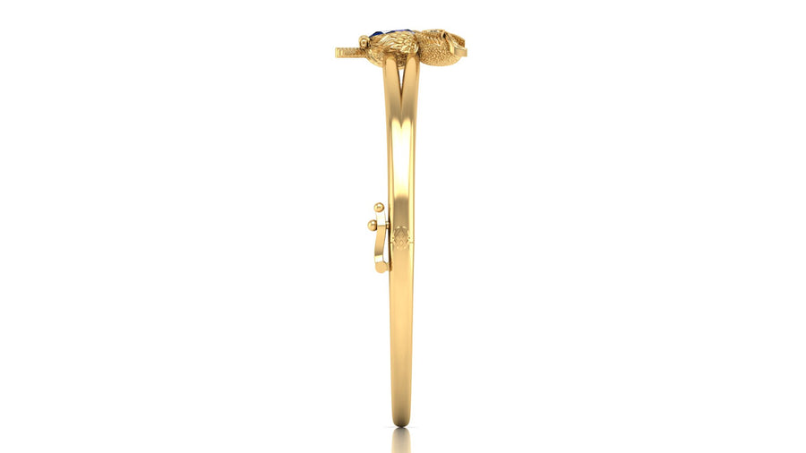 A gold bangle bracelet with a decorative snake head clasp and a small yellow sapphire gemstone, shown from the side on a white background.