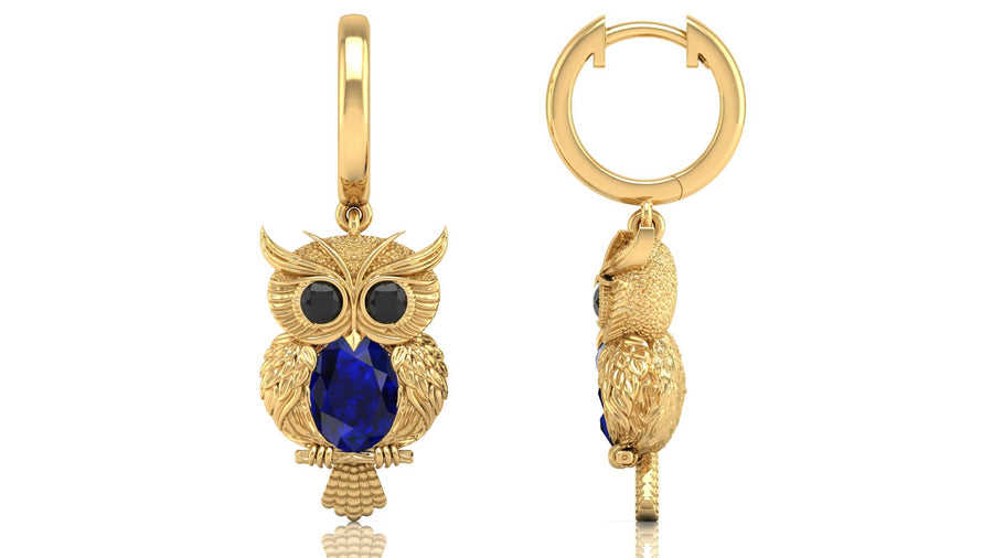 Gold owl-shaped earrings with blue sapphire gemstones on a white background