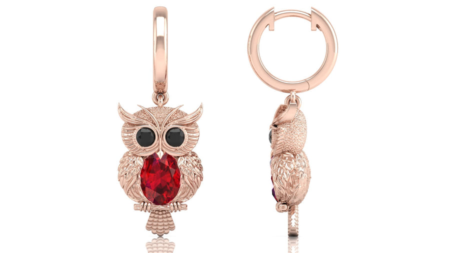 Rose gold owl-shaped earrings with ruby gemstones on a white background