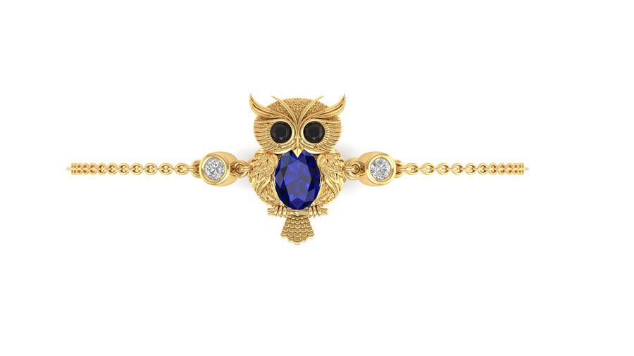 A gold owl pendant brooch featuring a large oval blue sapphire at its center, black gemstone eyes, and small clear stones, displayed on a delicate gold chain against a white background.