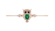 A rose gold owl pendant bracelet featuring a central green emerald and small clear accent stones, displayed on a clean white background.