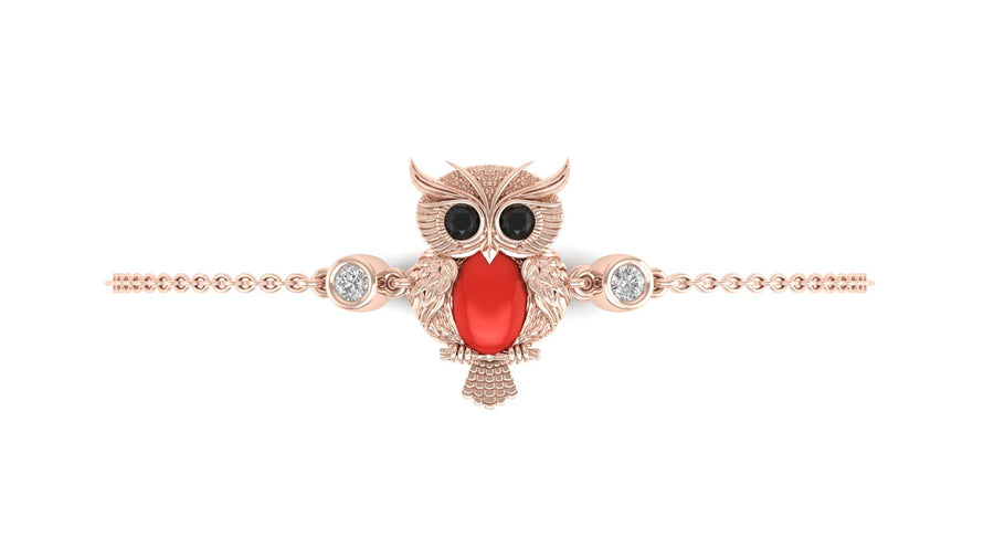 A rose gold owl charm bracelet with a red coral, black eyes, and clear gemstone accents, shown on a plain white background.