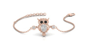A delicate rose gold chain bracelet featuring an owl pendant with black eyes and a central clear diamond gemstone, flanked by two small clear gemstones on the chain, set against a plain white background.