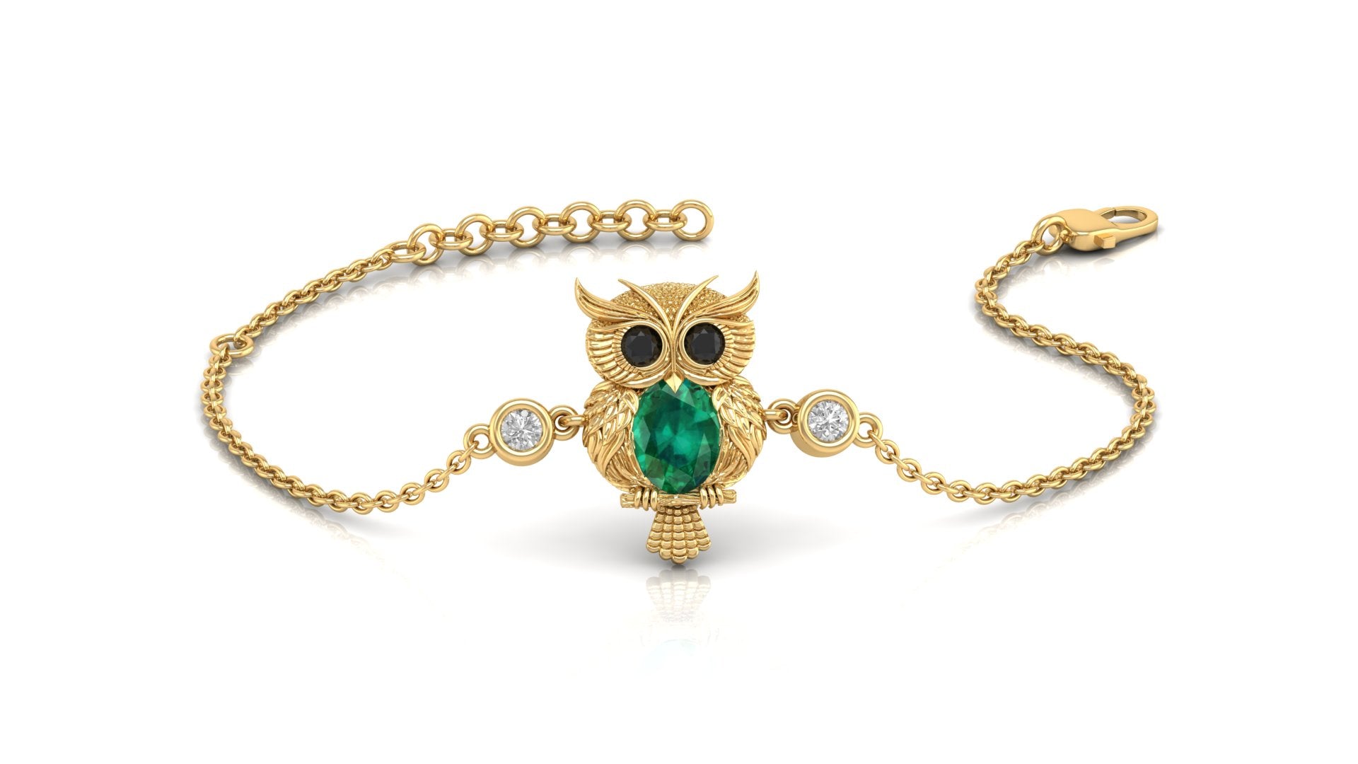 A gold chain bracelet featuring an owl pendant with a green emerald for a beak, black stones for eyes, and two small clear stones on either side, shown on a white background.