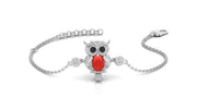 A silver chain bracelet featuring a central owl charm with a bright red coral gemstone on the centre, black eyes, and small clear stones, shown on a white background.