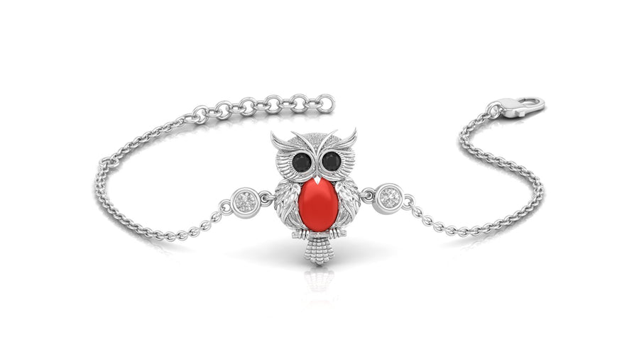 A silver chain bracelet featuring a central owl charm with a bright red coral gemstone on the centre, black eyes, and small clear stones, shown on a white background.
