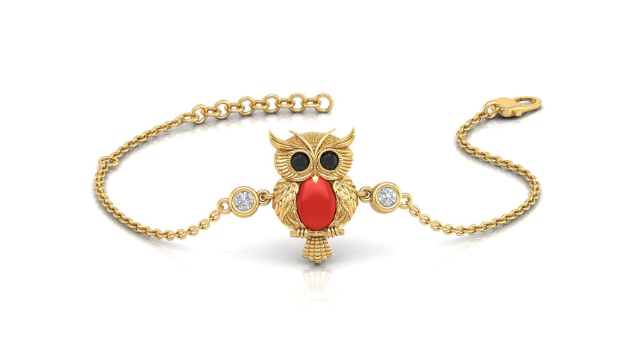 A gold chain bracelet featuring an owl pendant with a red coral for a beak, black stones for eyes, and two small clear stones on either side, shown on a white background.