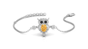A white gold-toned chain bracelet featuring an owl pendant with a large Yellow sapphire teardrop gemstone and small clear stones, shown on a white background.