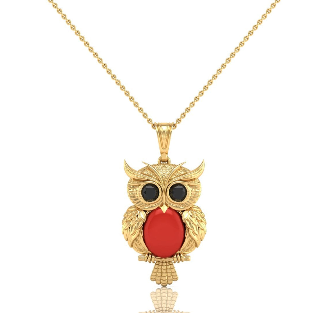 Gold owl pendant necklace with a red coral oval center and black eyes, suspended on a gold ball chain against a white background.