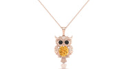 A rose gold owl pendant necklace featuring a large round yellow sapphire gemstone in the center, flanked by small black gemstone eyes, suspended from a delicate rose gold chain against a white background.