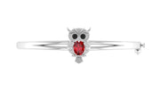 A white gold owl-shaped bangle bracelet featuring a red ruby gemstone in the center, flanked by small black and clear stones, shown on a plain white background.