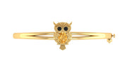 A gold bangle bracelet featuring an owl charm with black eyes and a yellow sapphire body, set against a plain white background.