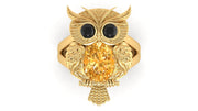 Gold owl-shaped ring with a yellow sapphire gemstone on a white background