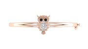 A rose gold bangle bracelet featuring an owl motif with a central clear round-cut gemstone and black eye accents, set against a plain white background.
